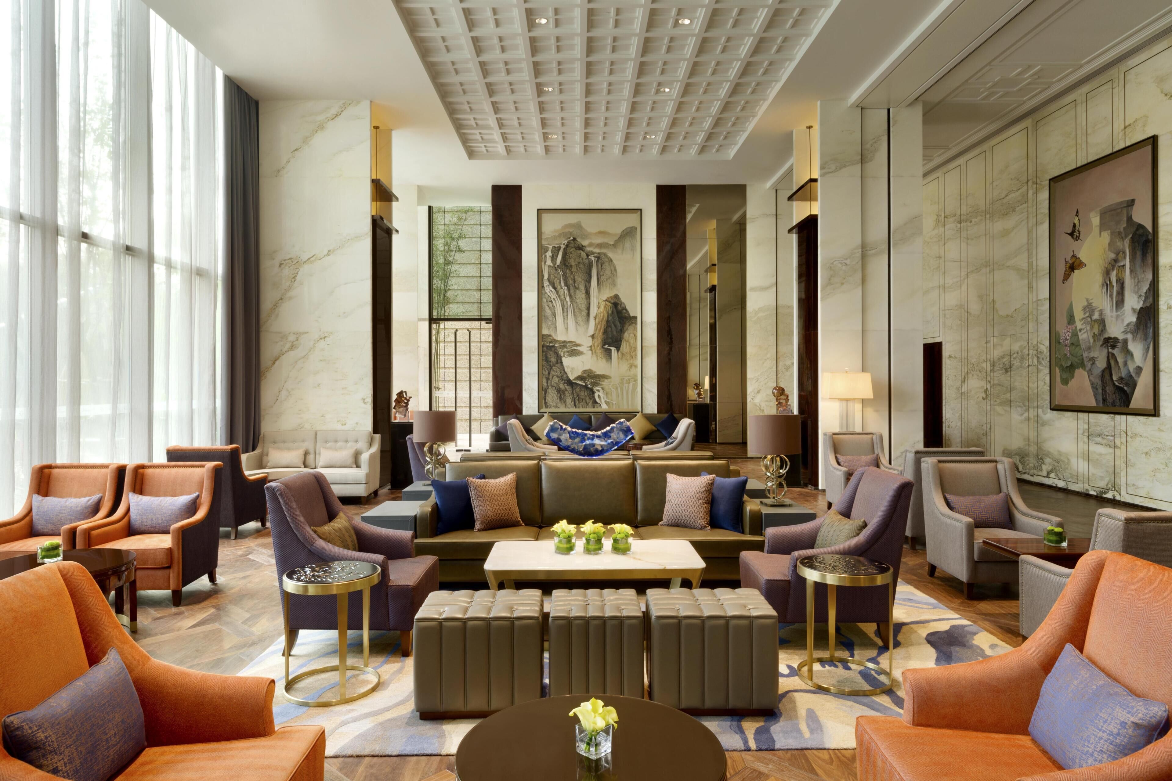A spacious lobby with a central seating area, a large window, and a marble wall.
