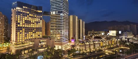 A high-rise hotel with multiple floors, a prominent red sign on top, and a well-lit surrounding area.