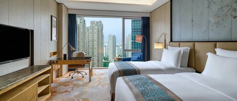 Habitación de hotel con una cama grande, un escritorio, un televisor y vistas a edificios altos.