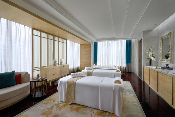A hotel room with two beds, a sofa, a small table, and a mirror.