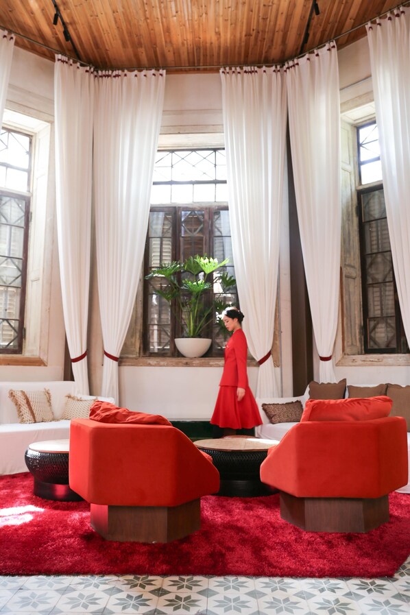 Una habitación con un ventanal grande, una planta en maceta y una persona vestida de rojo.