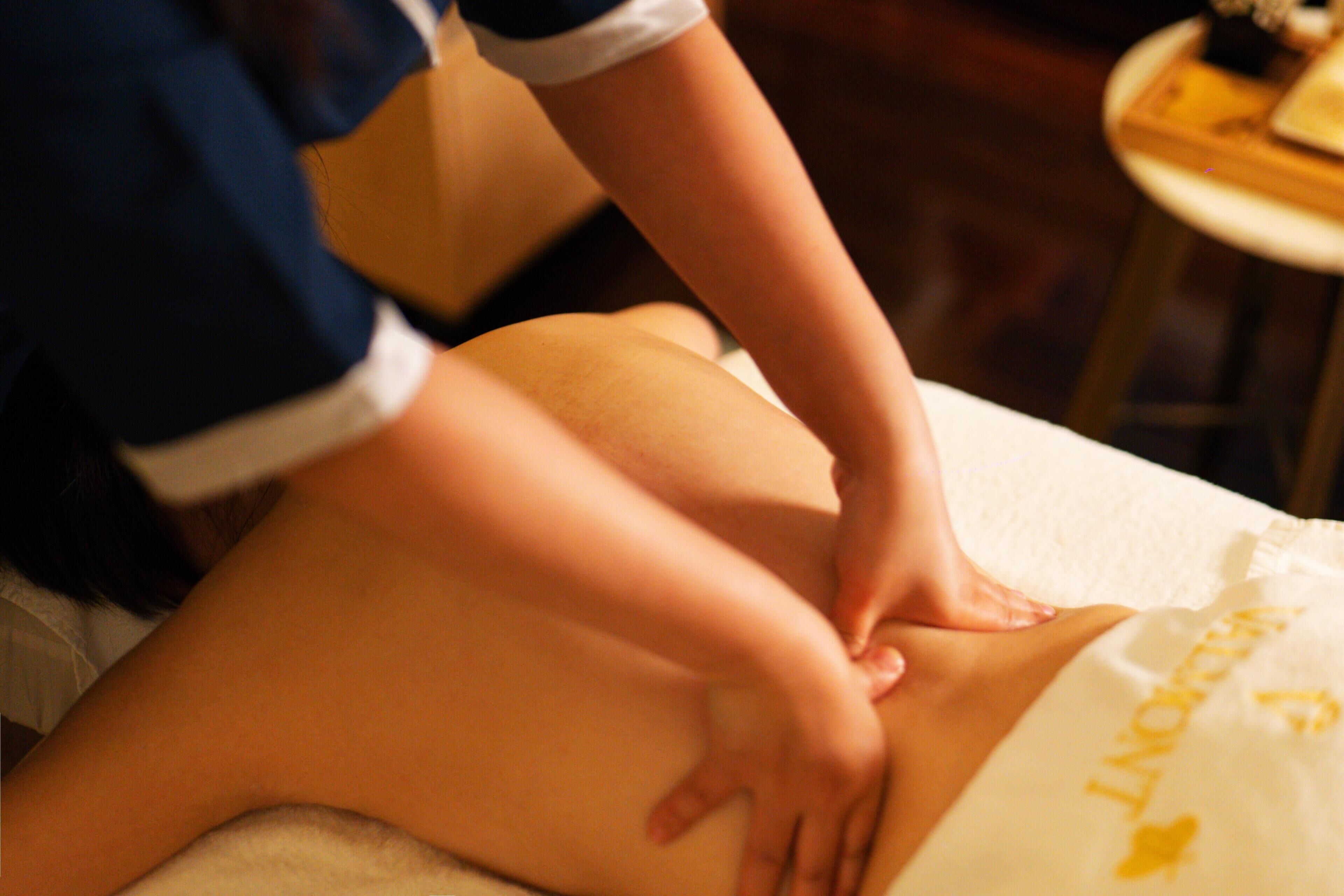 Eine Massagetherapie-Sitzung läuft, wobei die Hände des Therapeuten den Rücken des Klienten bearbeiten.