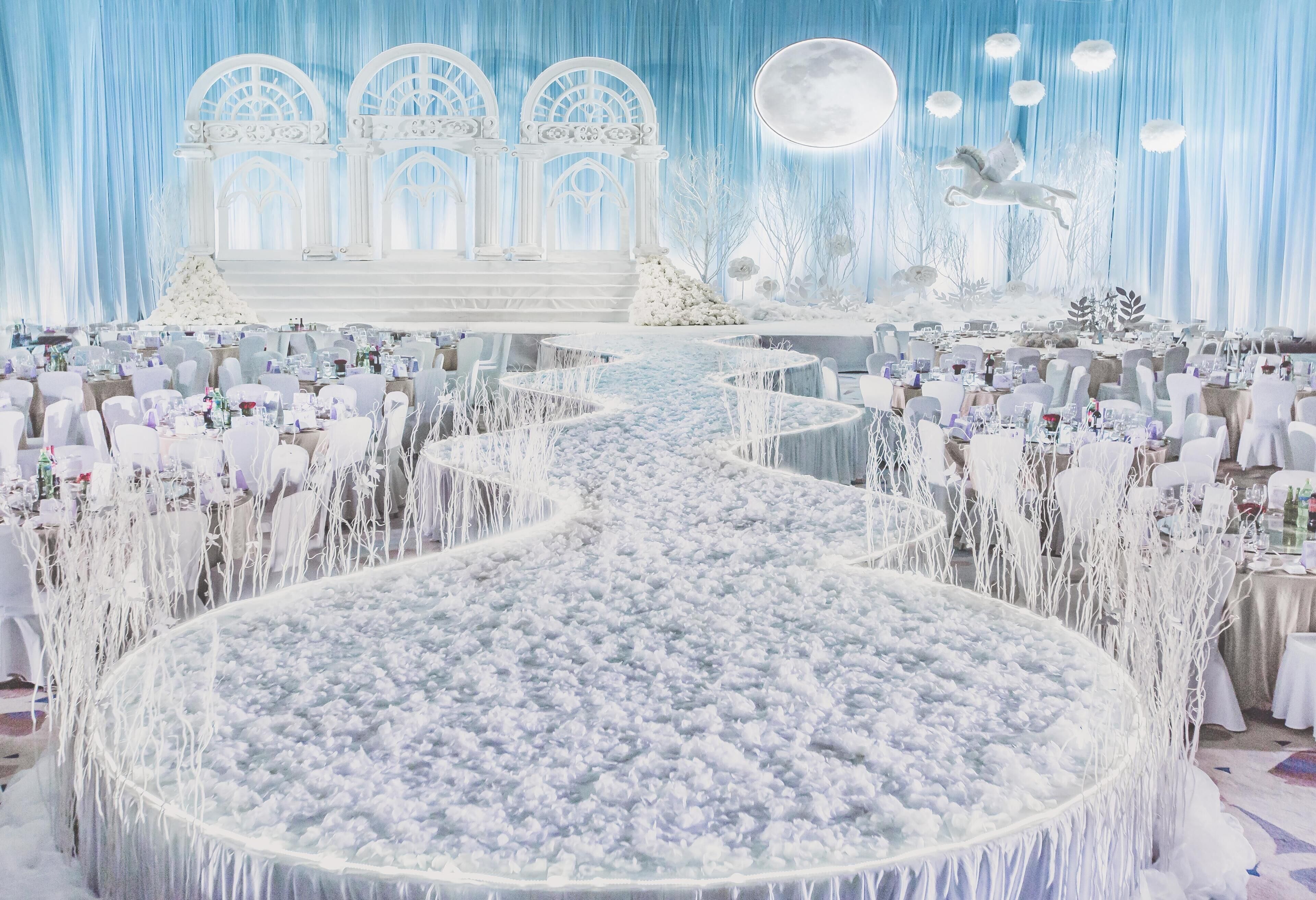 A venue with a central circular stage, white chairs, and a snowy-themed backdrop.