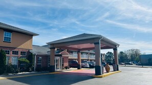 A covered parking area with a building in the background. - Budget Inn Beebe (Beebe)