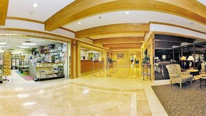 A hotel lobby with a spacious layout, a reception desk, and a seating area with a sofa and armchairs. - GetAways at Jockey Club (Las Vegas)
