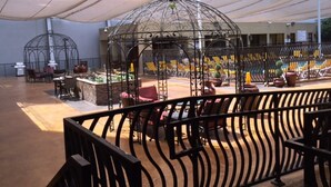 An outdoor seating area with a covered patio, metal chairs, and tables. - GetAways at Jockey Club (Las Vegas)