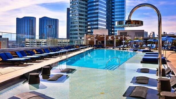 A rooftop pool with blue lounge chairs and a clear view of tall buildings in the background. - GetAways at Jockey Club (Las Vegas)