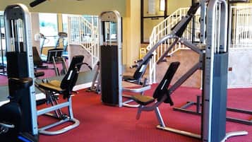 Une salle de sport équipée de divers appareils d’exercice, notamment des machines de musculation et un appareil d’escalier.
