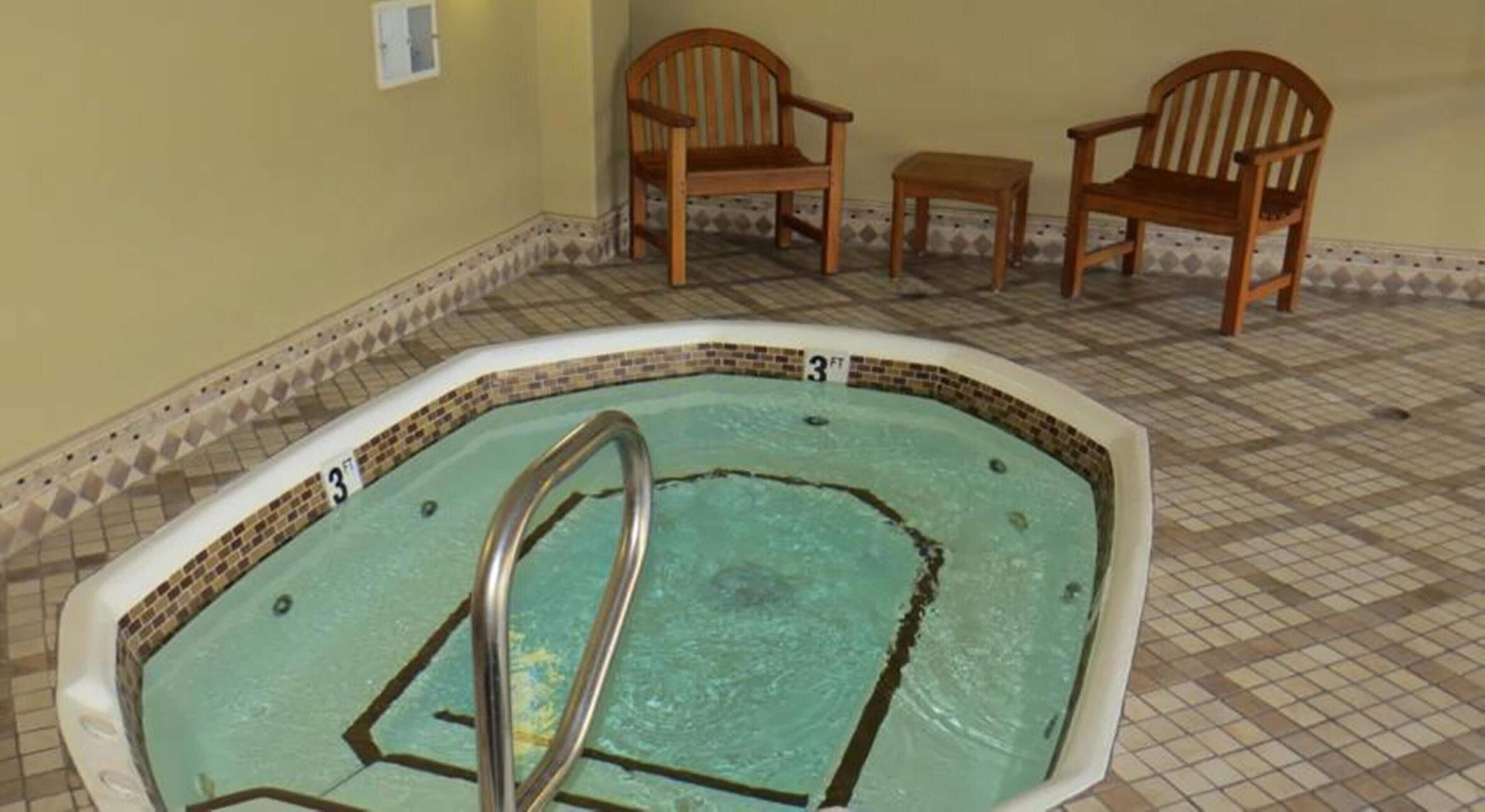 A small indoor swimming pool with a 3-foot depth marker, surrounded by wooden chairs and a small table.