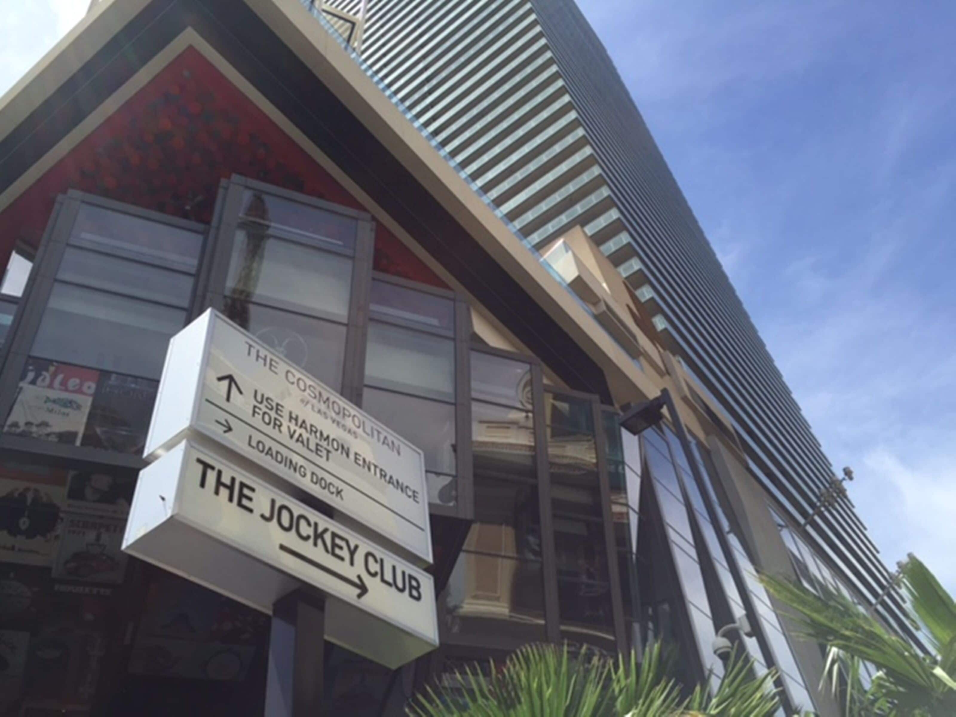 Un panneau indiquant l’hôtel The Cosmopolitan, avec des indications pour se rendre au Jockey Club.