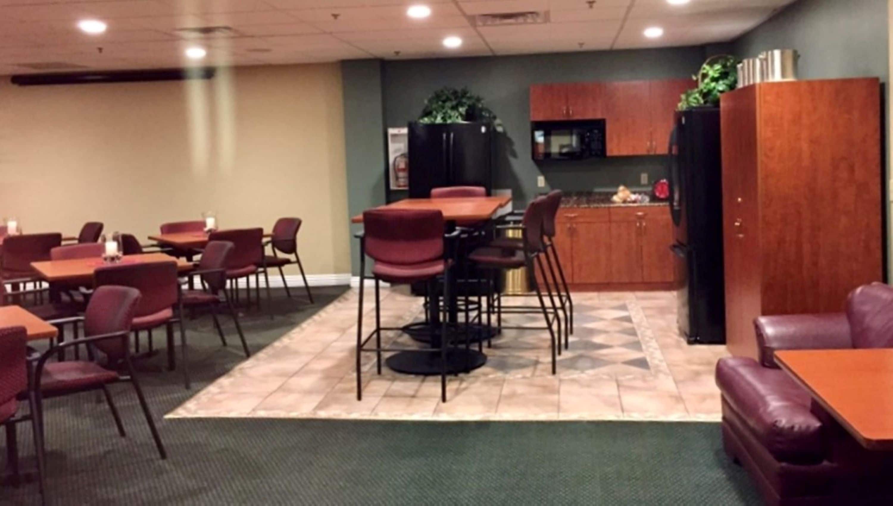 Une salle de conférence équipée de tables et de chaises, d’un coin cuisine et d’un espace détente avec un canapé.