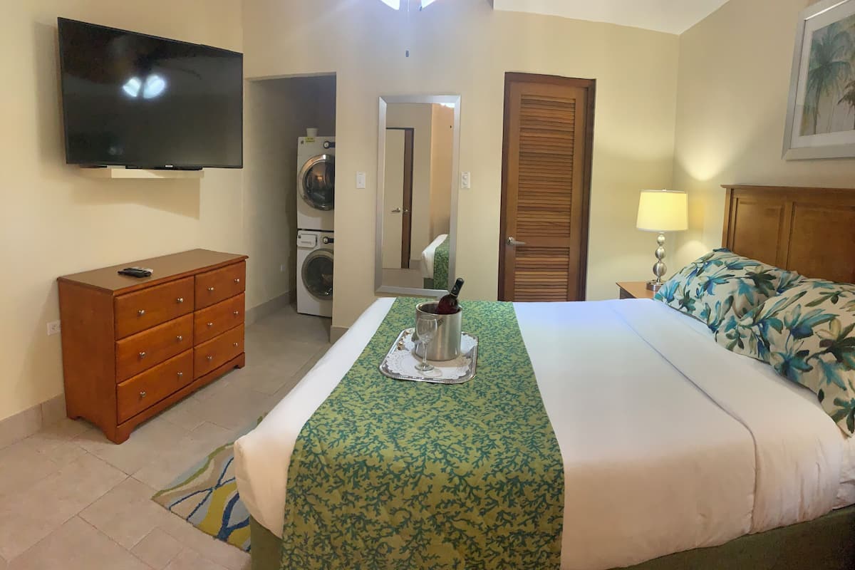 Ein Hotelzimmer mit einem Bett, einem Fernseher, einer Holzkommode, einer Waschmaschine und einem Spiegel.