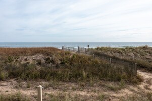 A sandy beach with a wooden fence and a signpost.