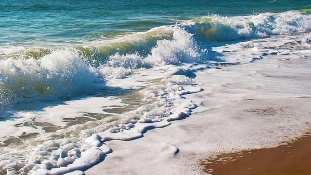 Een strand met golven die op de kust breken.