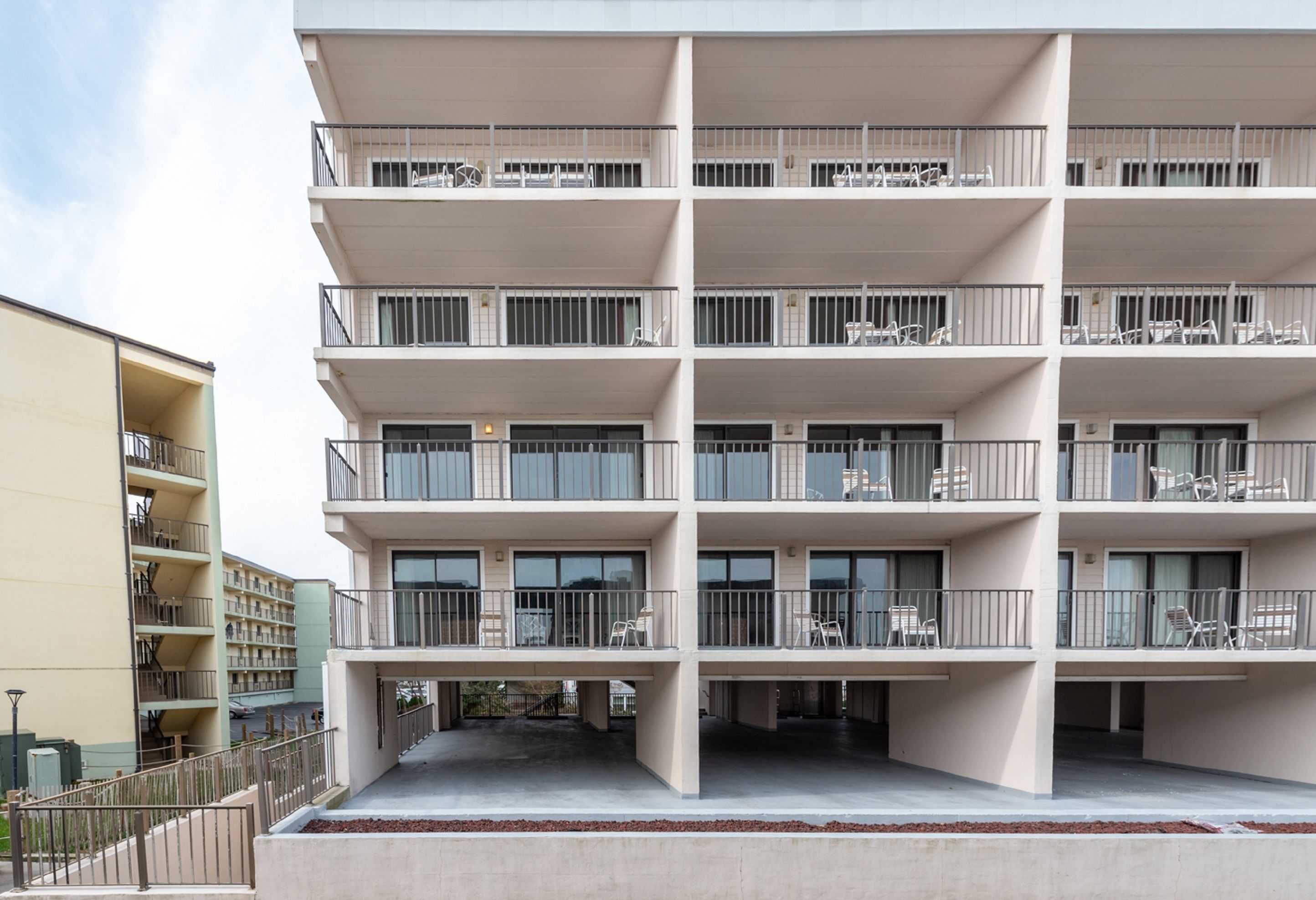 A multi-story building with balconies, each equipped with chairs and tables.