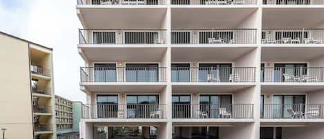 A multi-story building with balconies, each equipped with chairs and tables.