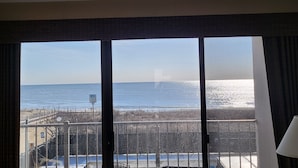 Een kamer met een groot raam met uitzicht op een strand en de zee.