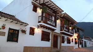 Un edificio tradicional blanco con balcones de madera y plantas en macetas.