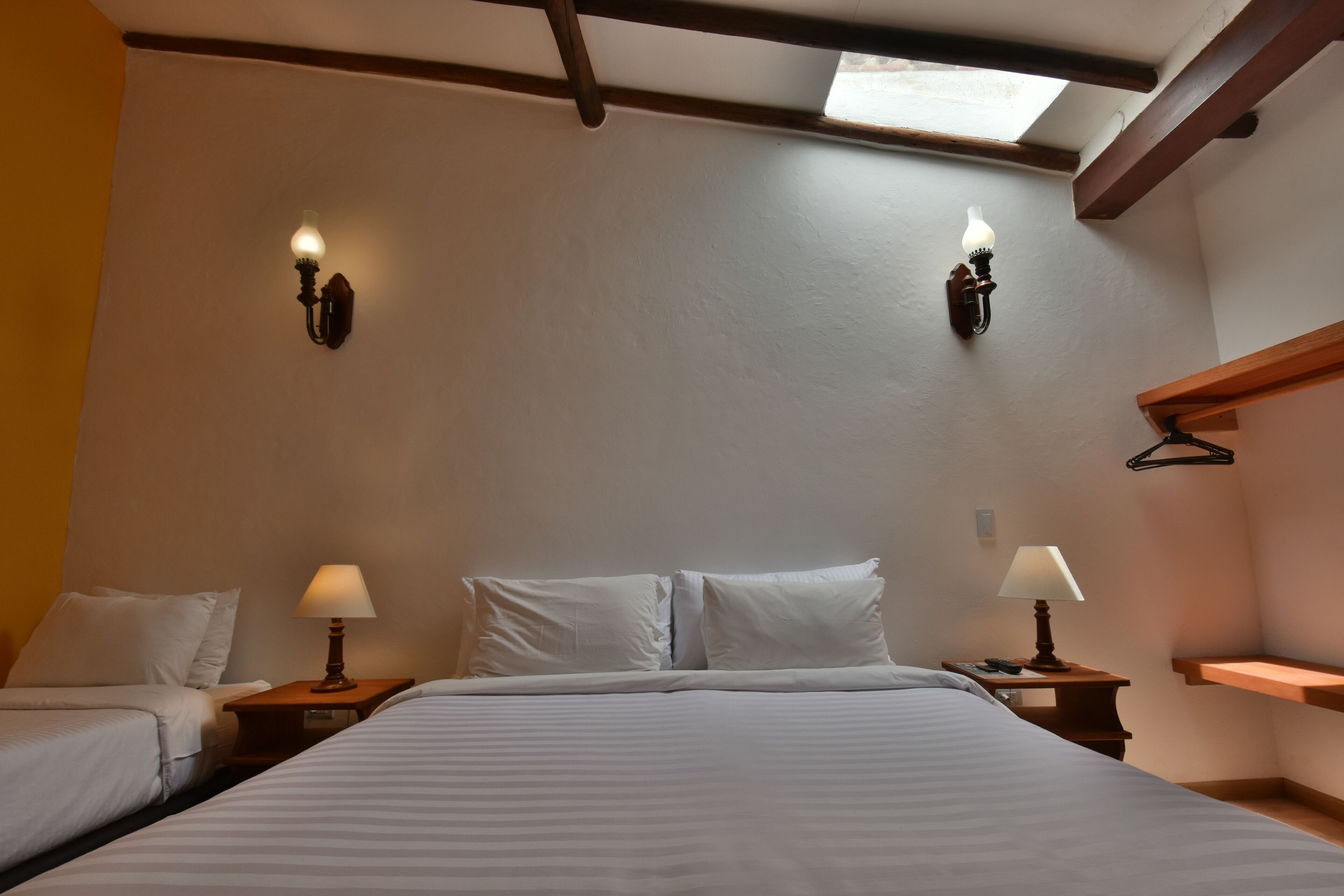 Un dormitorio con dos camas, lámparas de noche y un tragaluz.