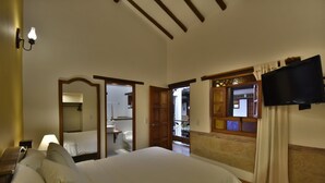 Habitación de hotel con una cama grande, un televisor montado en la pared y un baño visible a través de una puerta abierta.