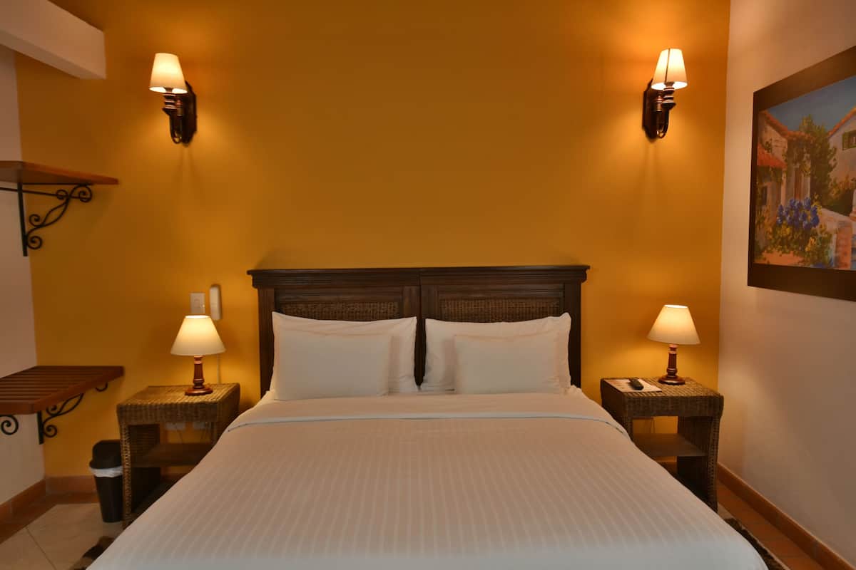 Ein Hotelzimmer mit einem großen Bett, zwei Nachttischlampen, einem Nachttisch und einem Bild an der Wand.