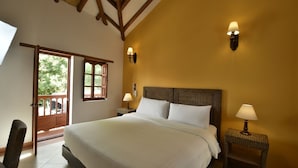 Een slaapkamer met een groot bed, twee bedlampen, een houten hoofdeinde en een balkondeur.