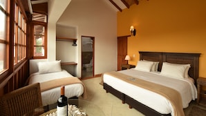 Een hotelkamer met twee bedden, houten hoofdeinden, een groot raam en uitzicht op de omgeving.