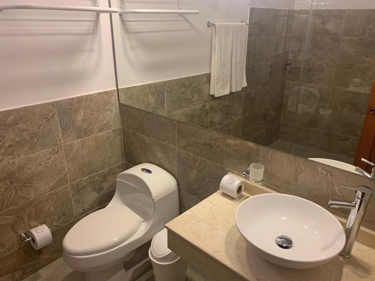 Un baño con inodoro, bidé, lavabo y cabina de ducha de vidrio.