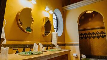 A bathroom with a vanity, two mirrors, a sink, and a window.