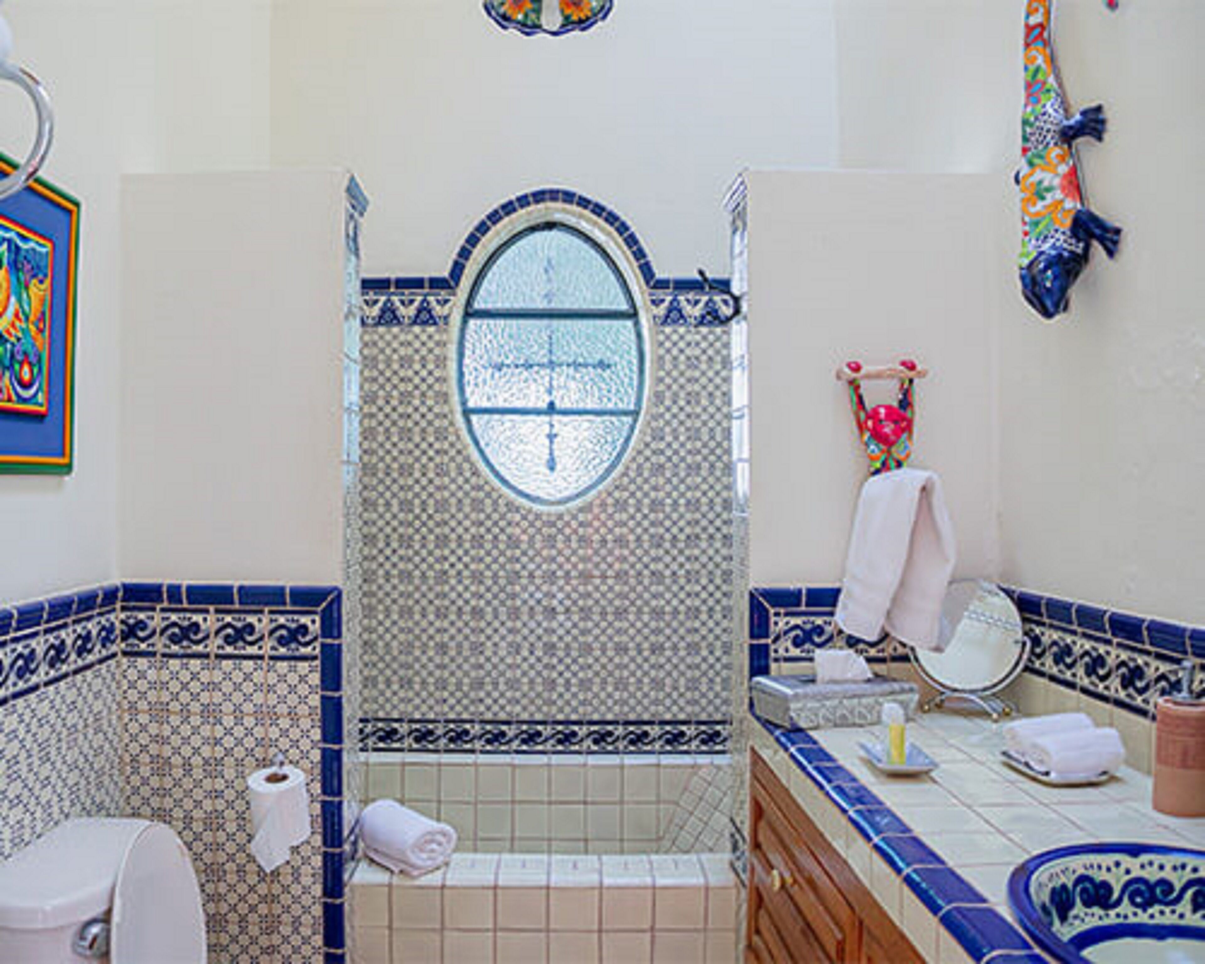 Un baño con piso de baldosas, un lavamanos con espejo, un perchero para toallas y un inodoro.