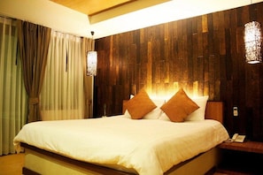 A hotel room with a large bed, wooden panel wall, and a nightstand with a lamp.
