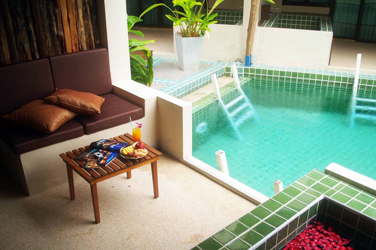 A pool area with a lounge chair, a small table with snacks, and a potted plant.
