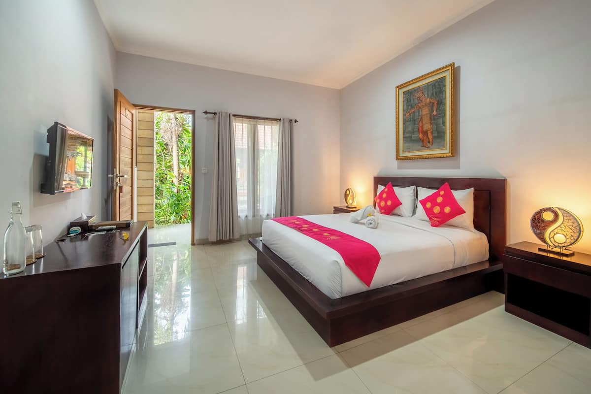 A hotel room with a bed, bedside tables, a desk, a television, and a door leading to a balcony.