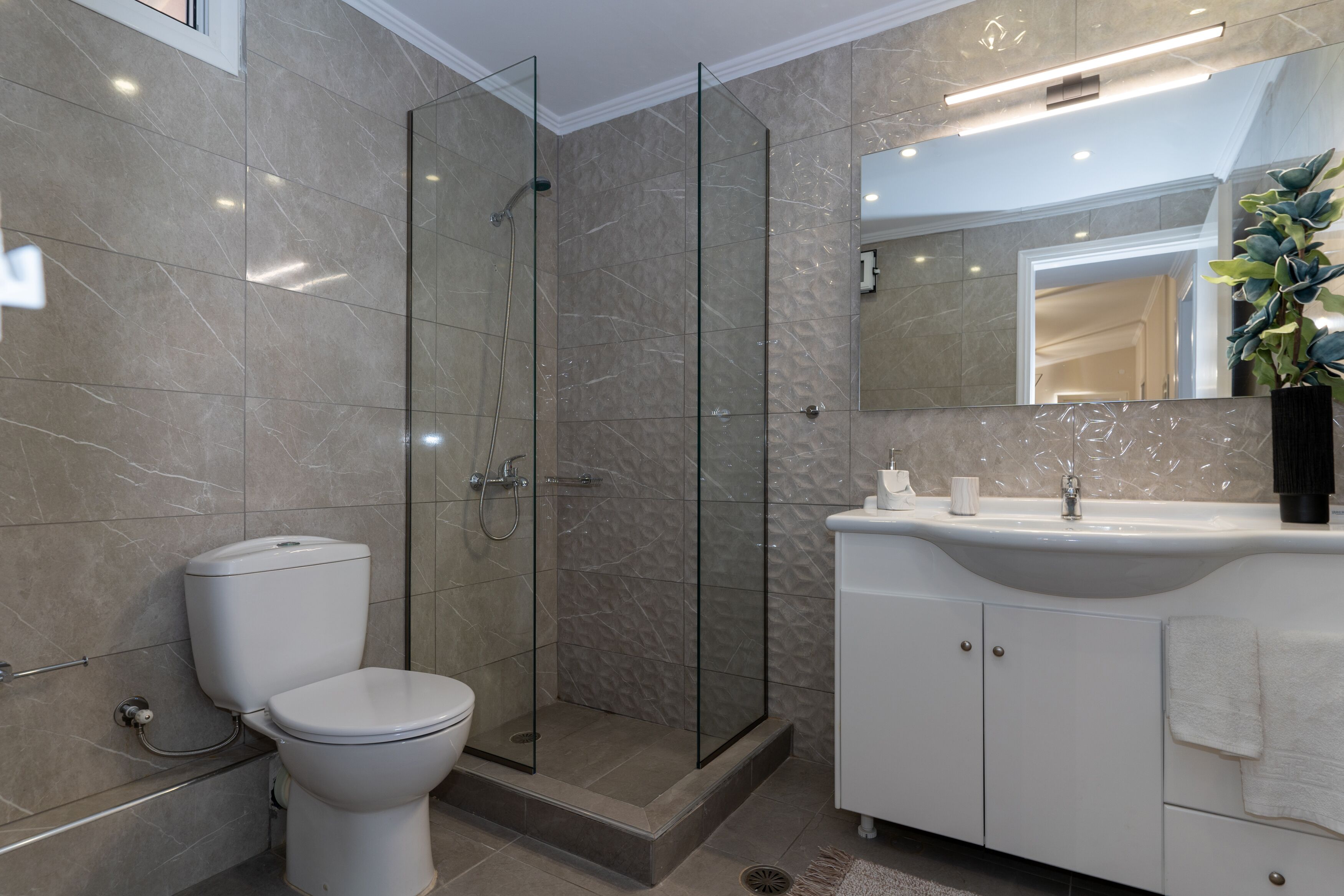 A modern bathroom with a glass-enclosed shower, a toilet, and a vanity with a sink.