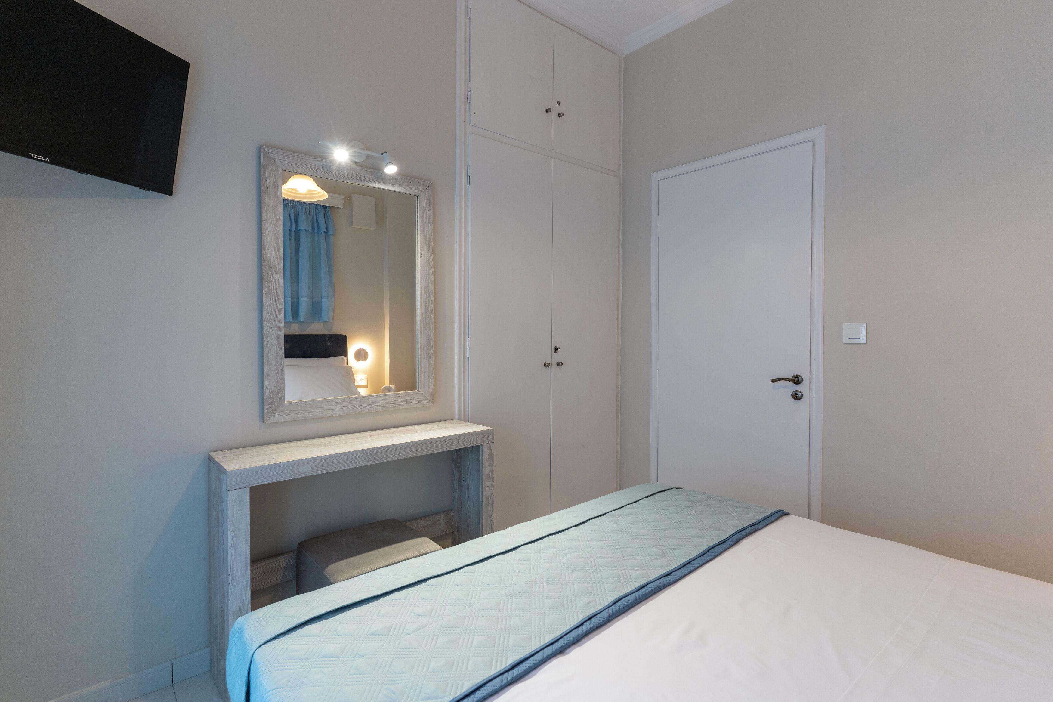 Un dormitorio con cama, mesita de noche, espejo y armario.