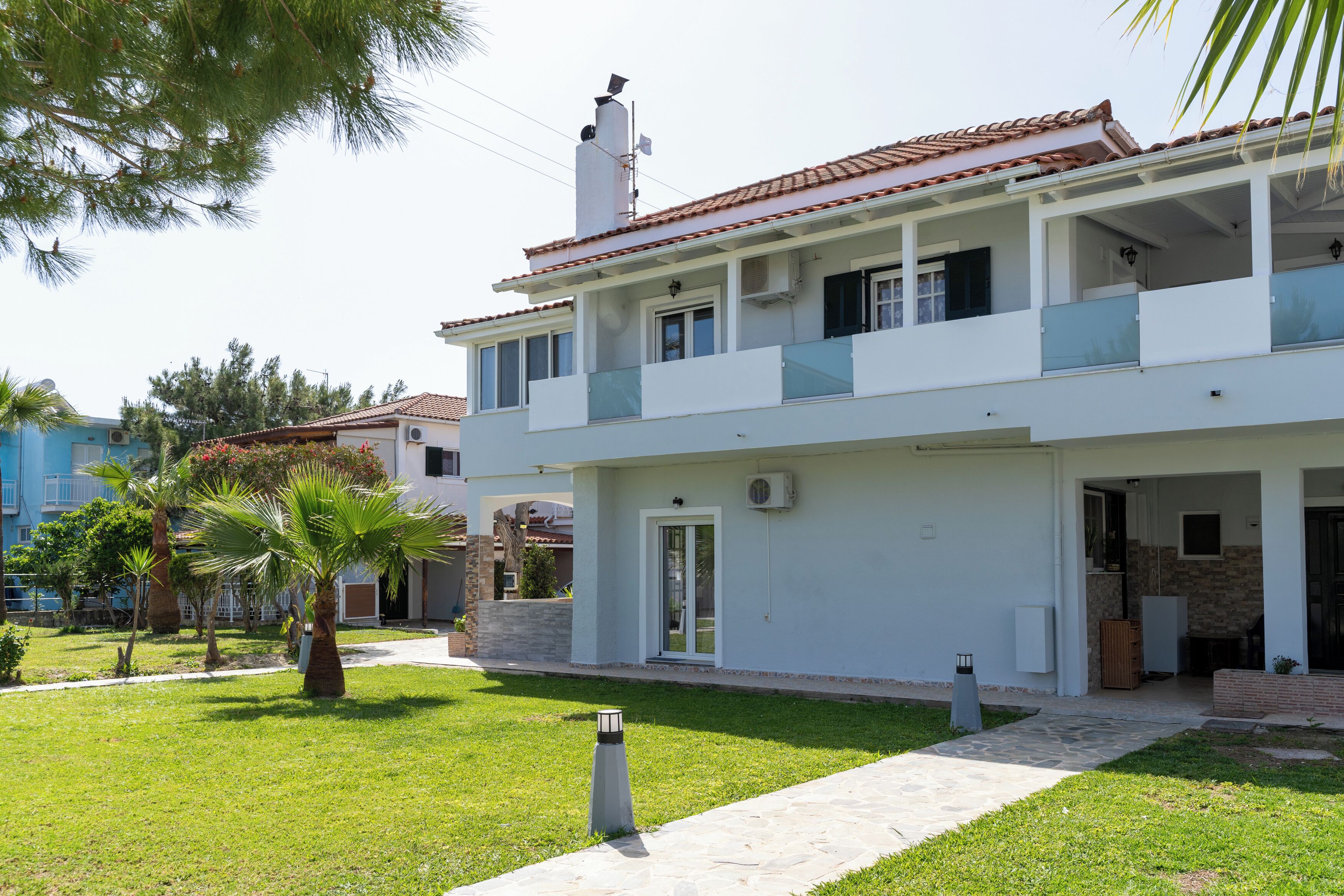 A two-story house with a balcony, a stone facade, and a well-maintained lawn.