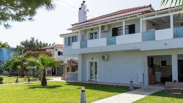 Una casa de dos pisos con balcón, fachada de piedra y césped cuidado.