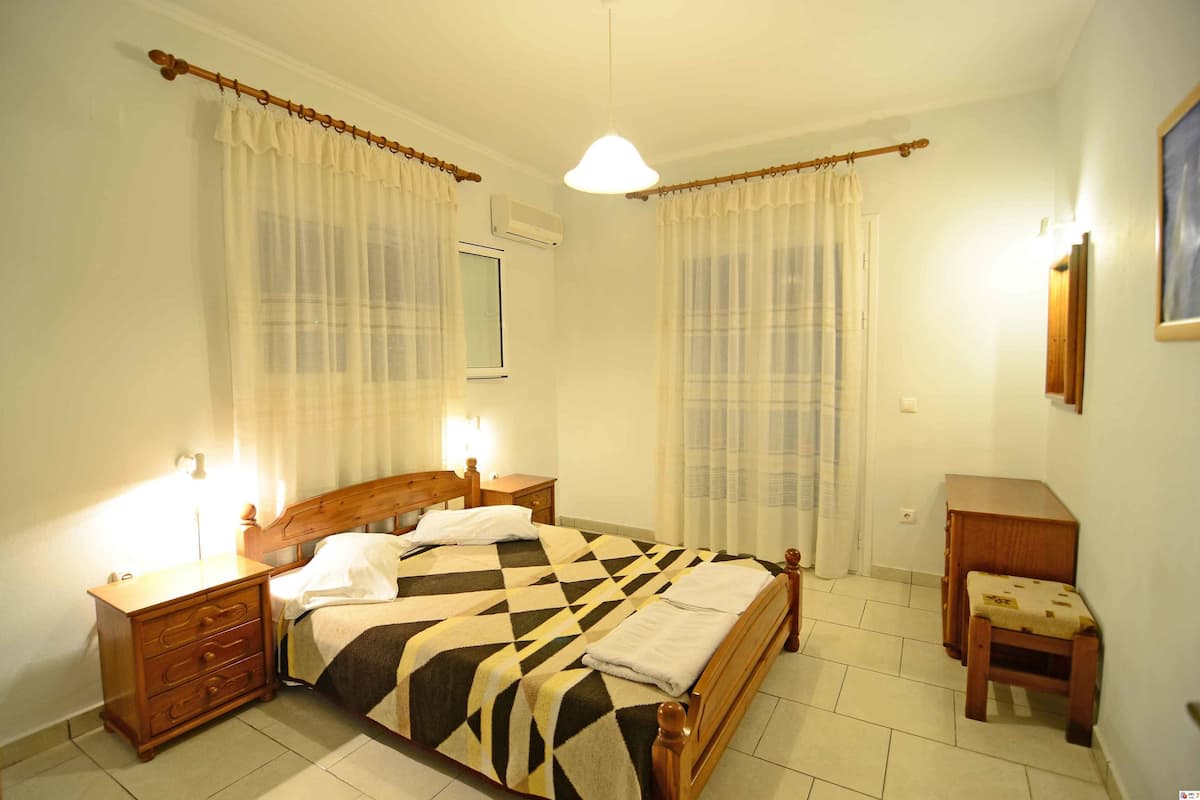 Une chambre à coucher comprenant un lit, des tables de chevet, une petite commode en bois, une chaise et une petite table.