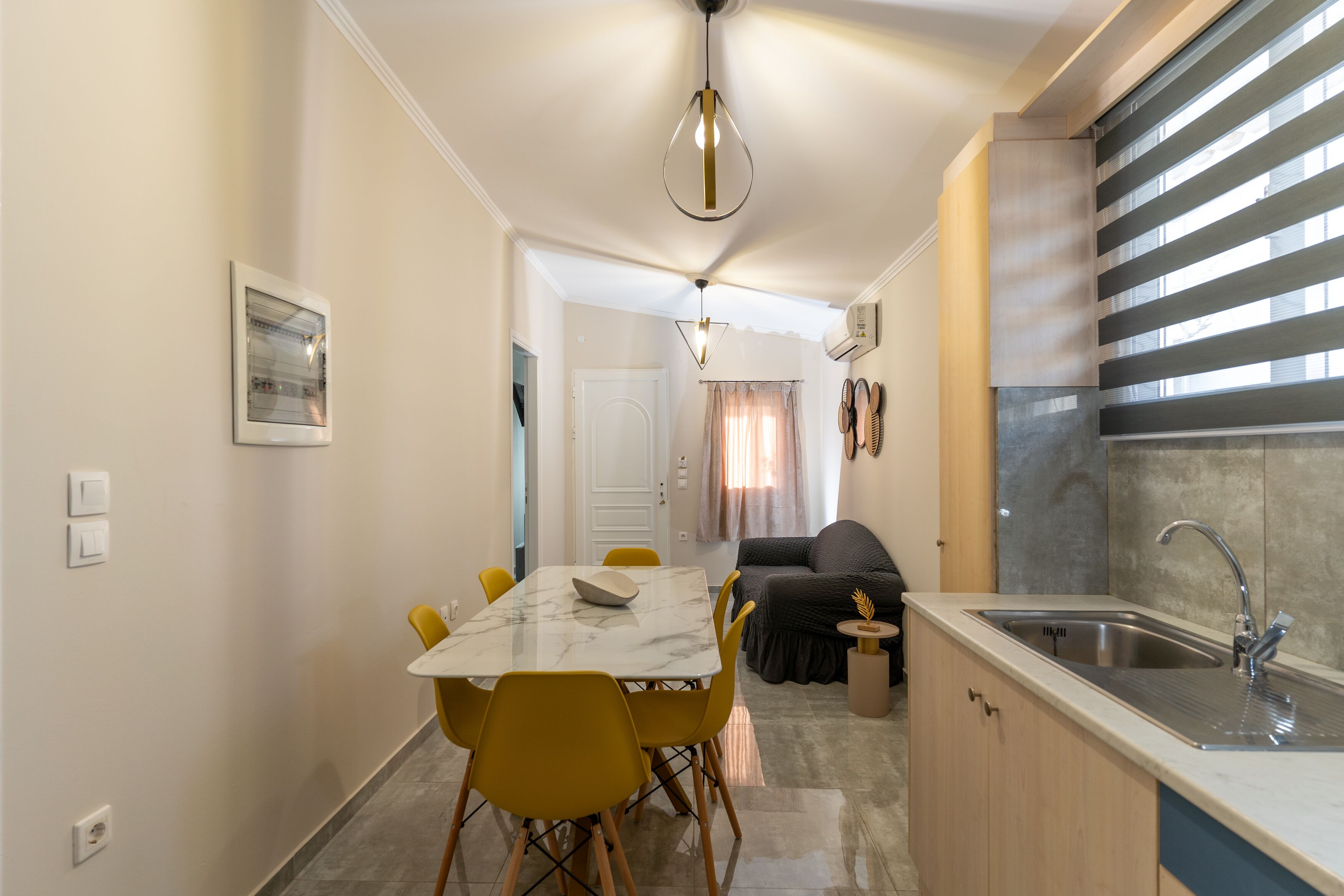A compact kitchen with a sink, a dining area with a table and chairs, and a living area with a sofa.