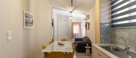 A compact kitchen with a sink, a dining area with a table and chairs, and a living area with a sofa.