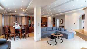 A spacious living area with a dining table, chairs, a sofa, and a coffee table.