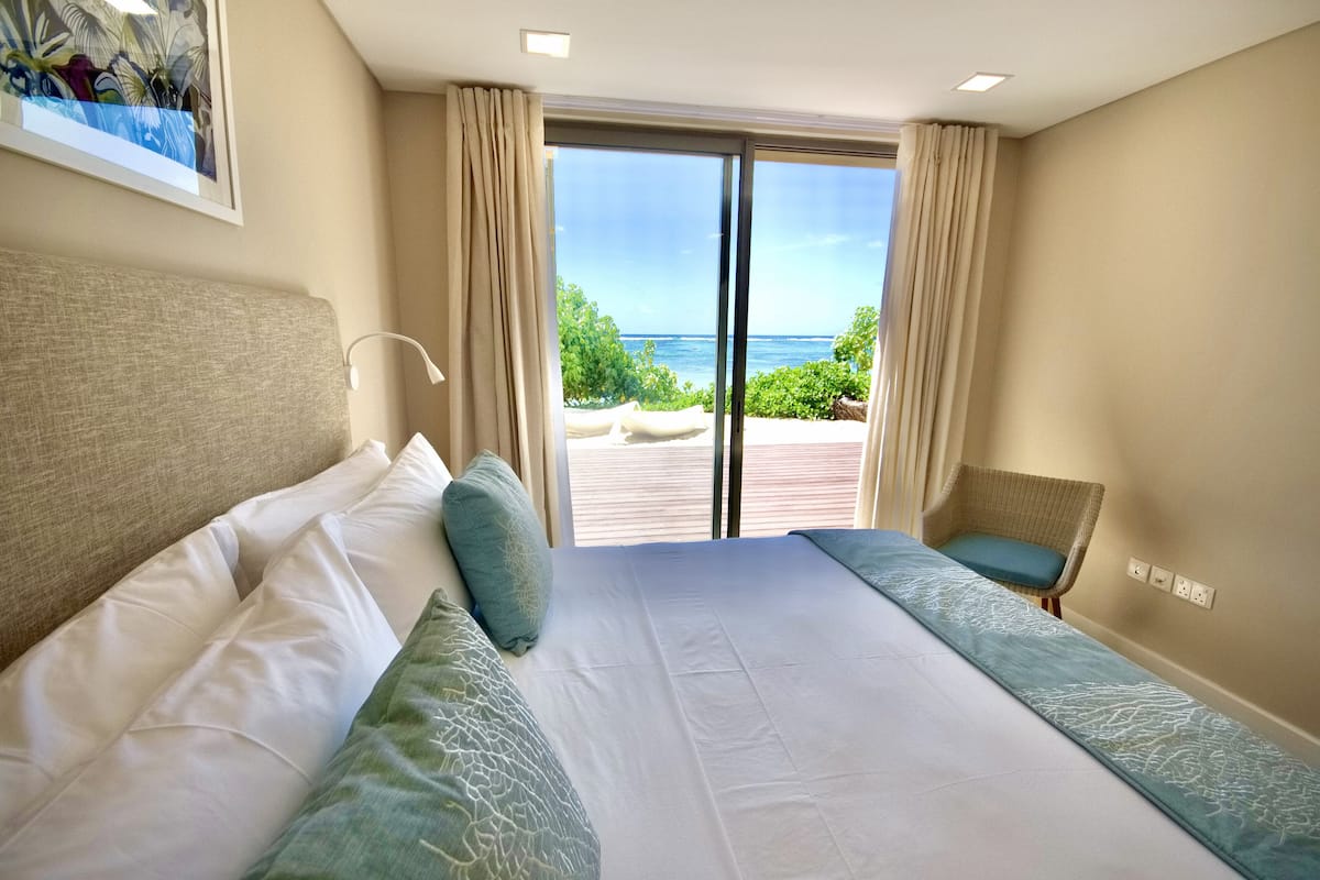 Un cuarto de hotel con una cama grande, una silla y vista al mar.
