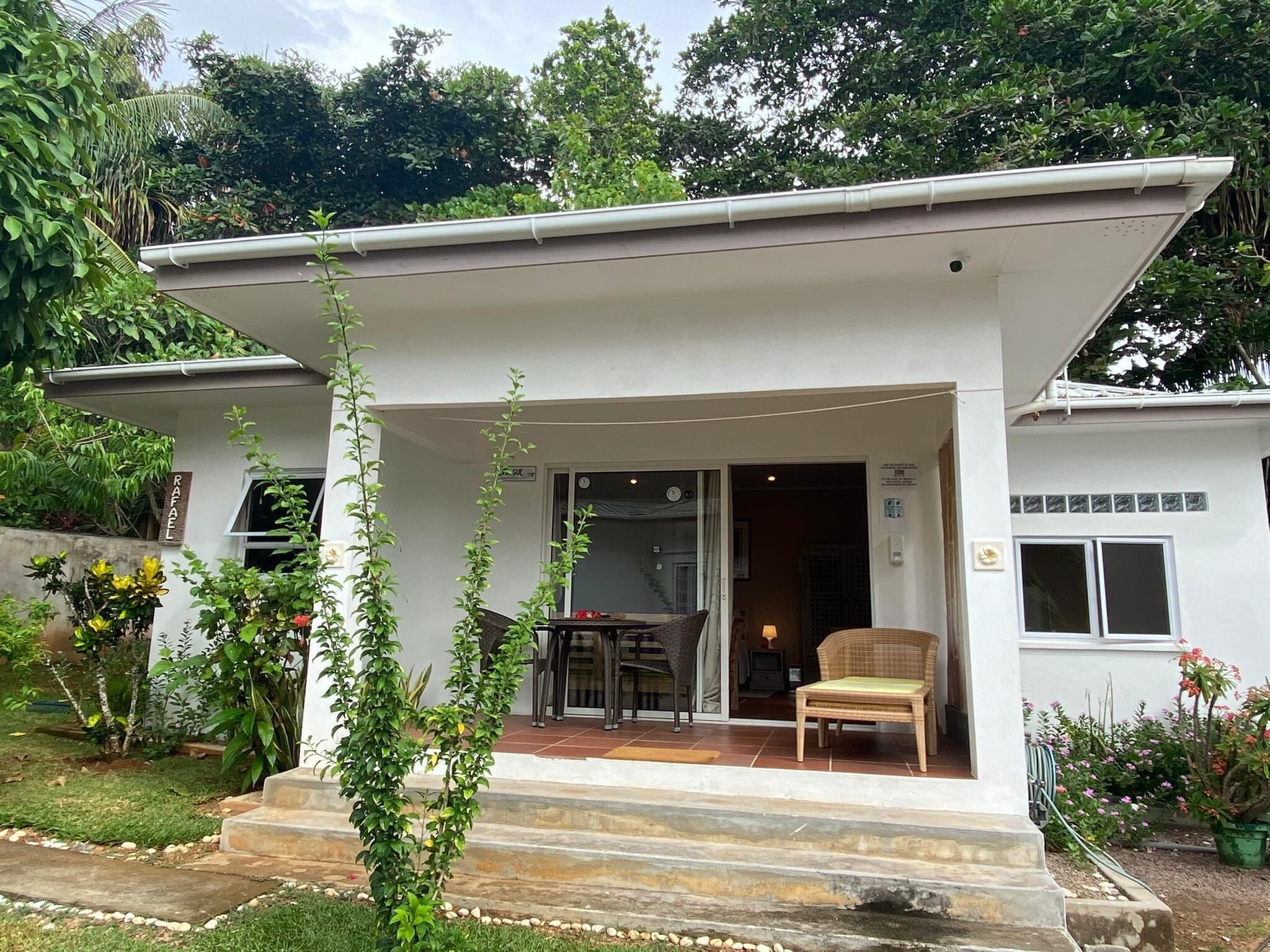A modern house with a covered porch, a dining area, and a visible staircase leading to the entrance.