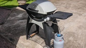 Una parrilla portátil con tanque de gas y un diseño en blanco y negro.