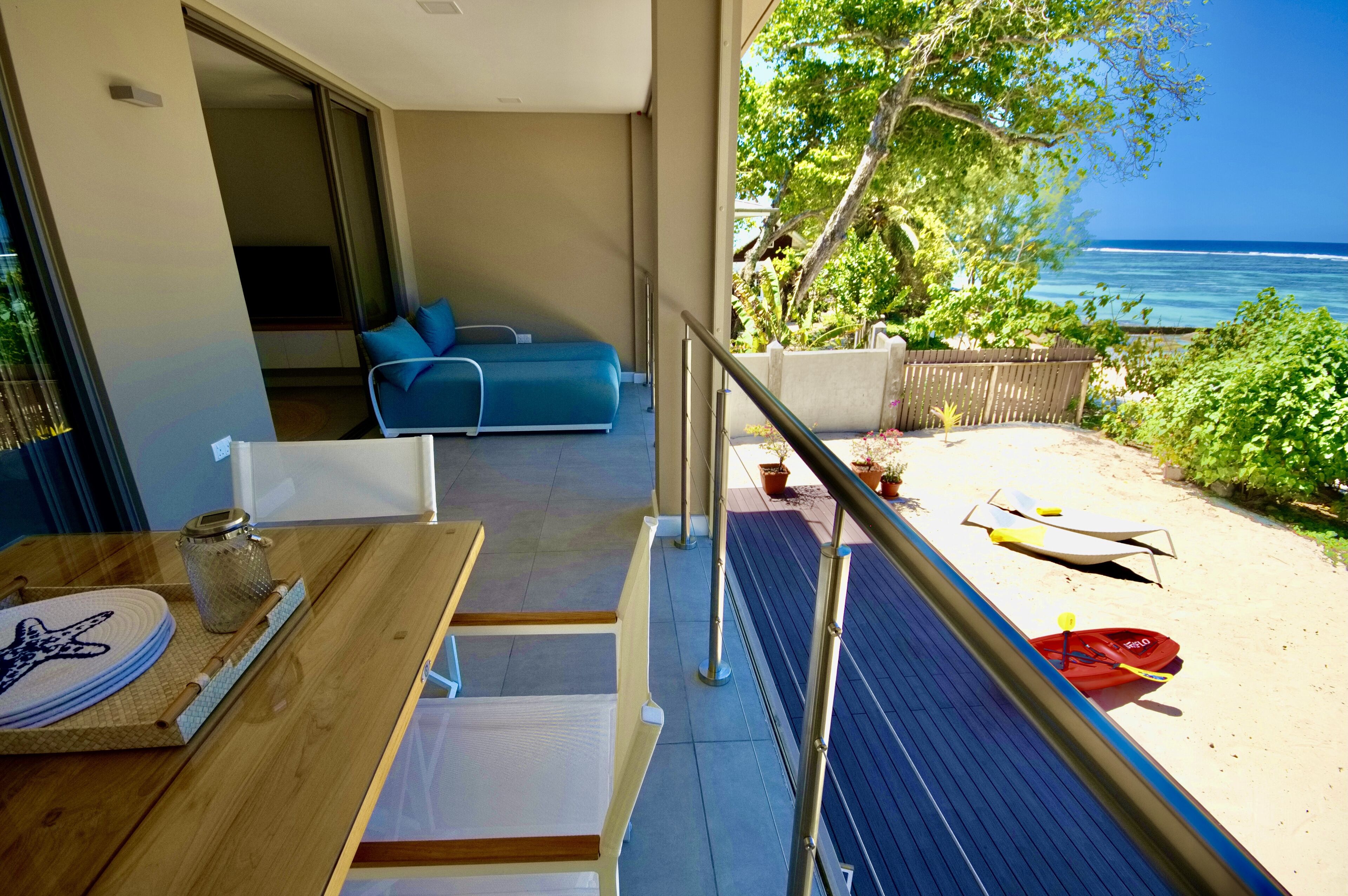 A balcony with a dining table, a sofa, and a view of the ocean.