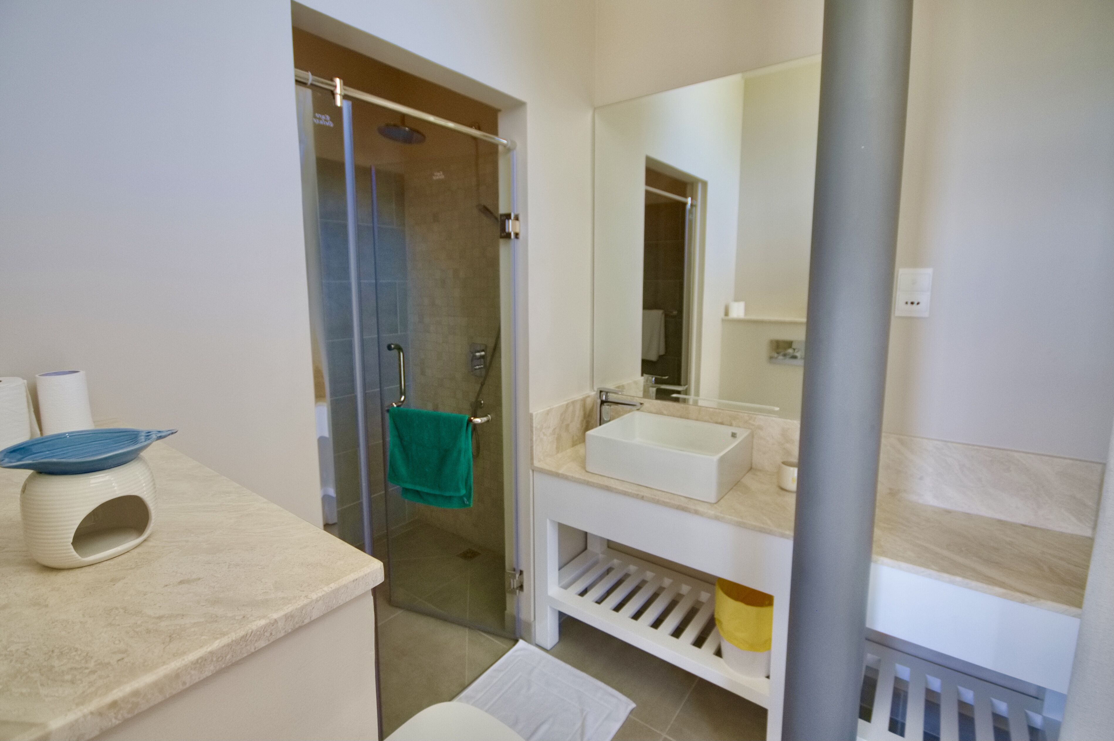 A modern bathroom with a glass-enclosed shower, a white sink, and a large mirror.