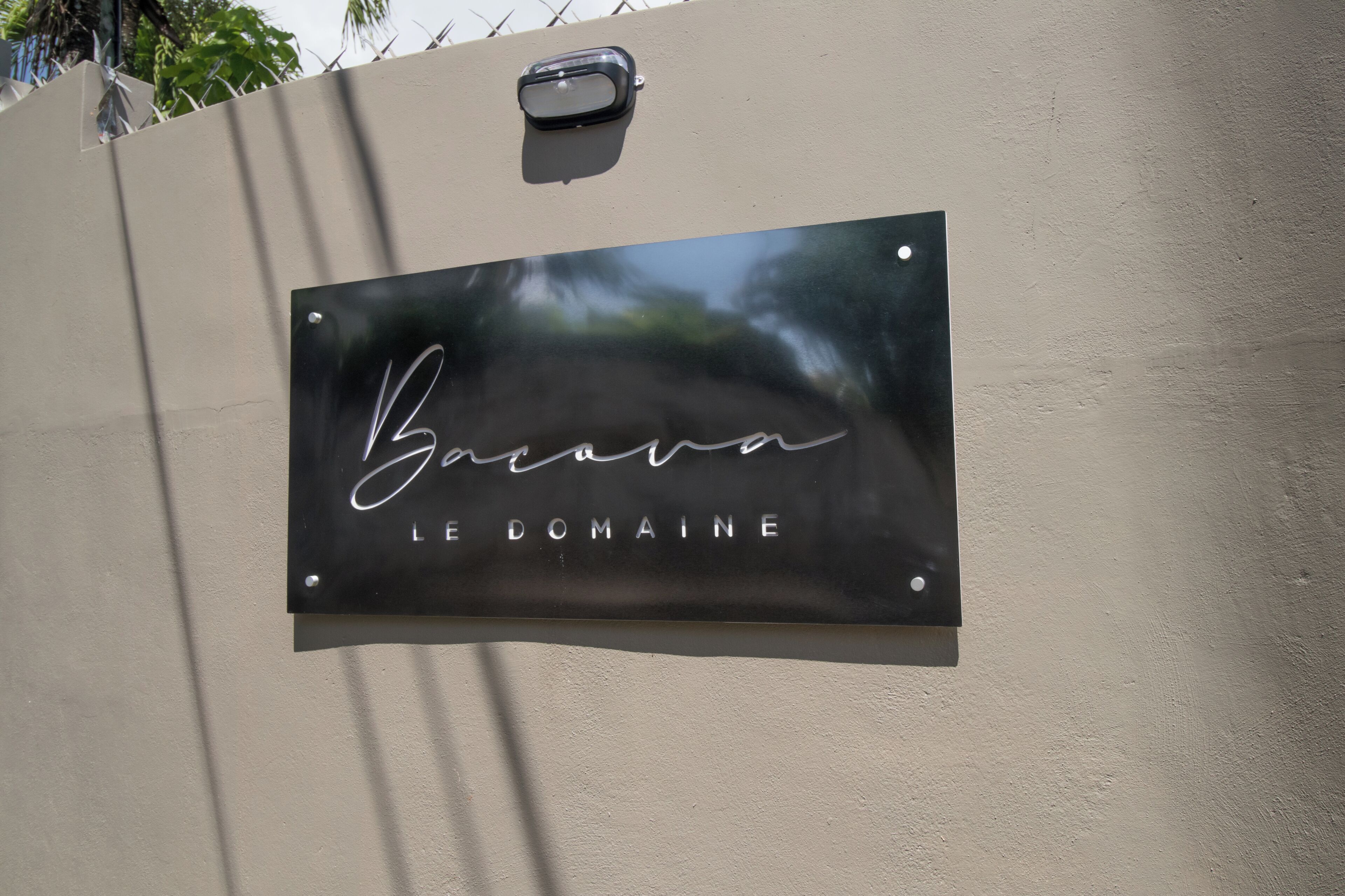 A metal sign with 'Le Domaine' written on it, mounted on a wall.