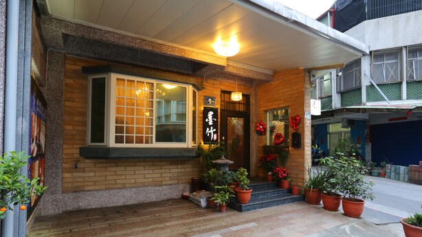 A building with a brick facade, a large window with a grid pattern, and a sign with Japanese characters. - Mozhu B&B (Hualien City)