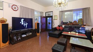A living room with a television, sofa, ottoman, and a chandelier. - Mozhu B&B (Hualien City)