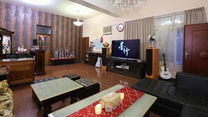 A living room with a television, a sofa, a dining table, and a chandelier. - Mozhu B&B (Hualien City)
